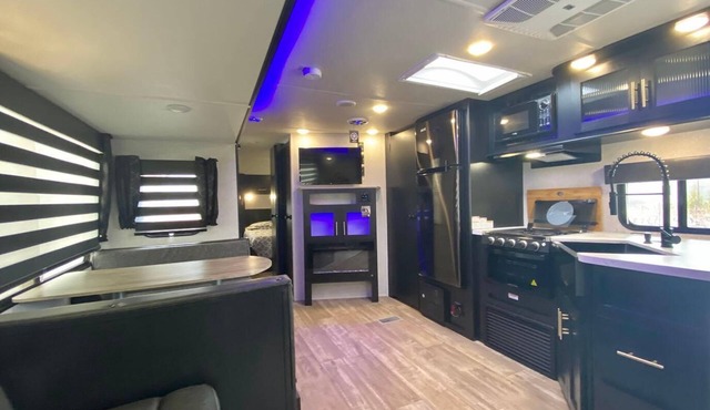 Cherokee RV features a queen-sized bed, dining area, and full kitchen.